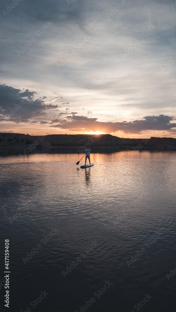 Man standing on a stand up paddling board during the sunset at Lake Mead in Nevada, USA