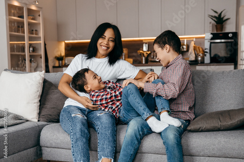 Happy african american family mom and two sons fooling around and having fun at home together