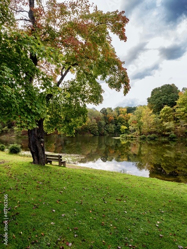 Tomlinson Run State Park in the fall in West Virginia with the fall colors and trees reflecting in the lake, the blue cloud filled sky in the background and a tranquil serene nature landscape scene. photo