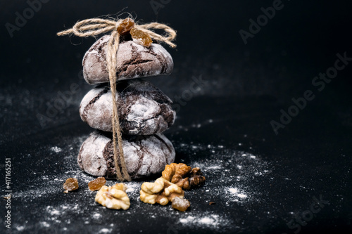Chocolate cookie with nuts, raisins and flour. Chocolate crinkle cookies on dark black background. recipe concept. Chocolate cookies in powdered sugar on black background.