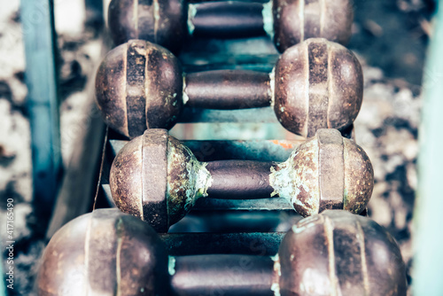 Retro old rusty dumbbells in a diagonal row on public gym