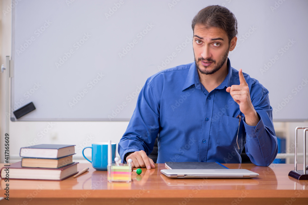 Young male teacher physicist sitting in the classroom Young male teacher physicist sitting in the classroom