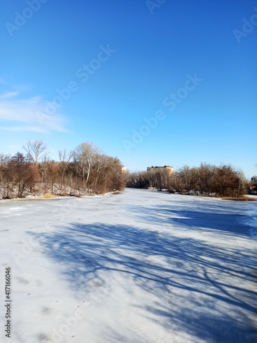 Winter landscape, white ice on a frozen river with blue sky