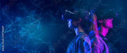 Future game and entertainment digital technology. Teenager having fun play VR virtual reality glasses sport game 3D cyber space futuristic neon colorful virtual metaverse background. photo