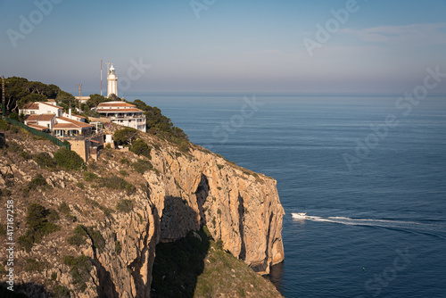 Residential area and lighthouse on top of a cliff on the coast of Cape Nao in Javea on a summer day with blue sky, Javea, Alicante, Spain