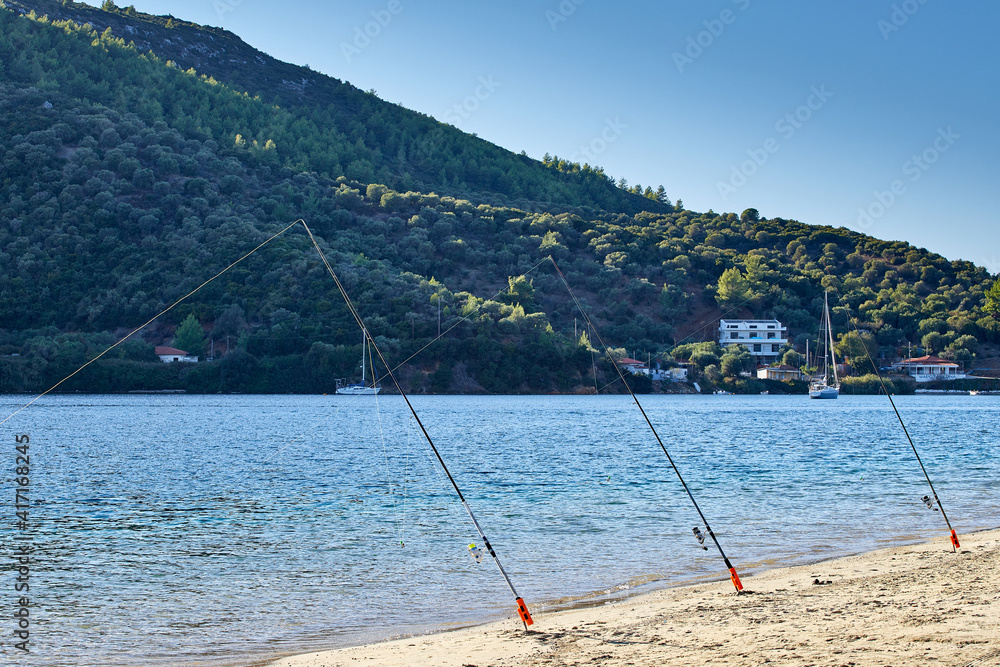 Three fisher rods lines on a sandy beach in Porto Coufou, Halkidiki, Greece