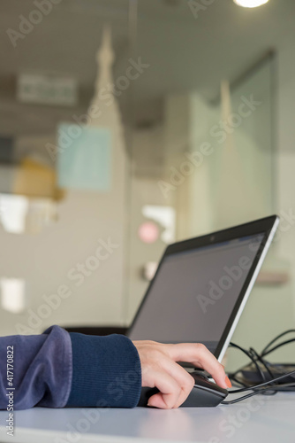 Side view of a working woman is typing on laptop computer with blank copy space screen for texting a message. Working time as concept. 