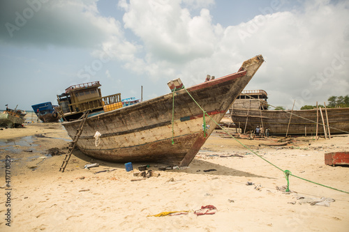 An old fishing boat is being repaired in the harbor by several workers