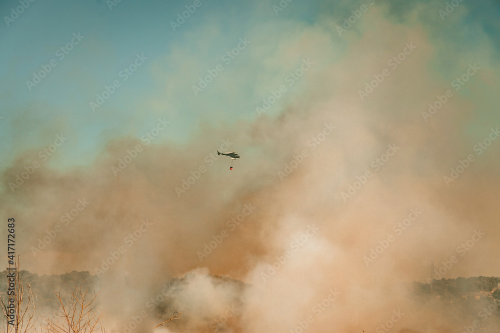 Helicóptero apagando un incendio en el que el fuego crea mucho humo Helicóptero apagando un incendio en el que el fuego crea mucho humo