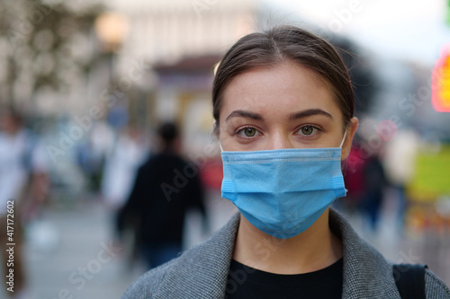 Young woman in blue medical protective mask on a crowded street