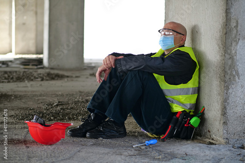 Worker in goggles and protective mask sits at construction site