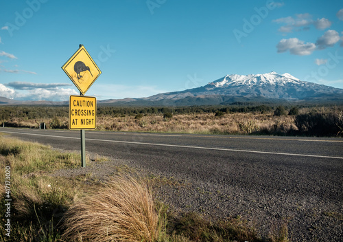 Kiwi crossing sign next to snowy Mount Ruapehu in New Zealand's Tongariro national park.