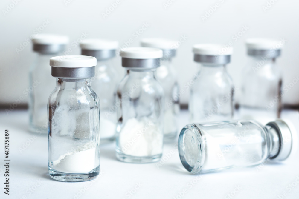Glass sealed vials with medicine in powder form on light background, selective focus Glass sealed vials with medicine in powder form on light background, selective focus