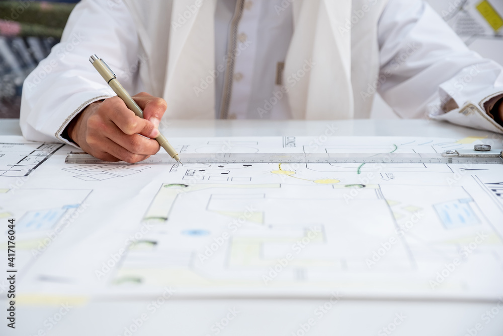 Architect's hand with pencil drawing on the paper sheet Architect's hand with pencil drawing on the paper sheet