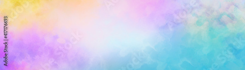 Colorful watercolor background of abstract sunset sky with puffy clouds in bright rainbow colors of blue purple yellow and soft white center blur