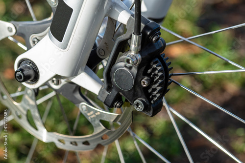 Hydraulic front disc brake on mountain bike with bicycle hub, caliper and spokes.