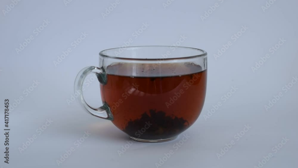 Tea leaves rotate in a glass goblet. Tea leaves rotate in a glass goblet.