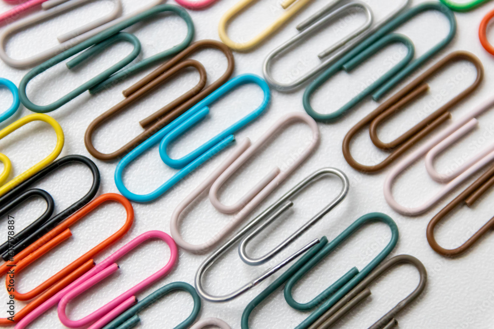 Many colorful paper clips on a home office desk for stationary design as colorful pattern to tidy desk, papers and paperwork to attach attachments to files and documents or collection of office supply Many colorful paper clips on a home office desk for stationary design as colorful pattern to tidy desk, papers and paperwork to attach attachments to files and documents or collection of office supply