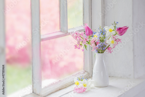 spring flowers in white vase on old windowsill