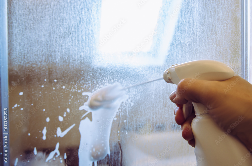 Person hand using limescale remover chemical foam. Descaling shower case  glass door. Work in progress. Stock Photo | Adobe Stock