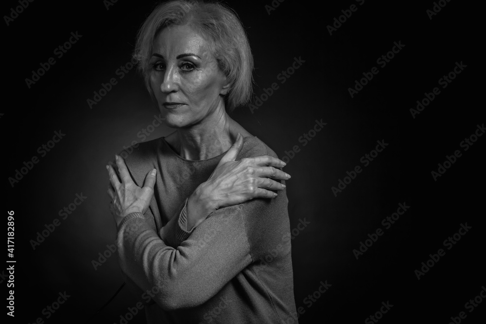 Classic black-and-white dramatic portrait of an elderly blonde woman in Studio on black background