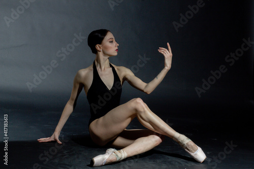 dramatic vintage portrait of a girl, dancing ballerina in a black bodysuit in the Studio on gray background