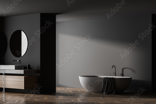 Modern bathroom interior with sink and white bathtub in eco minimalist style with brown wooden parquet floor. And two round mirrors. Light and shadows from window. No people. 3D Rendering