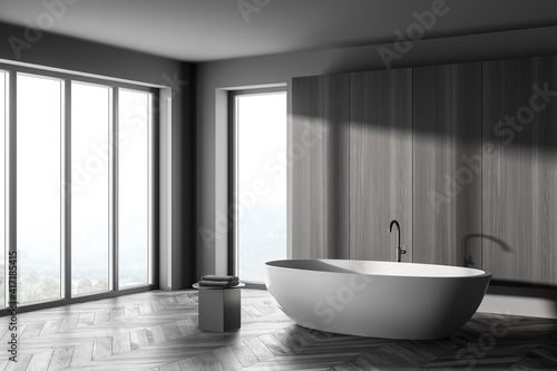 Corner Interior of modern bathroom with grey wooden walls  concrete floor  comfortable white bathtub.