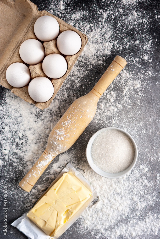 Baking ingredients: flour, eggs, butter and sugar, with rolling pin on a table Baking ingredients: flour, eggs, butter and sugar, with rolling pin on a table