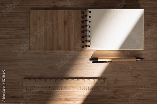 notebook, pen and bamboo ruler on a wooden board. Warm sunset light cast shadows. photo