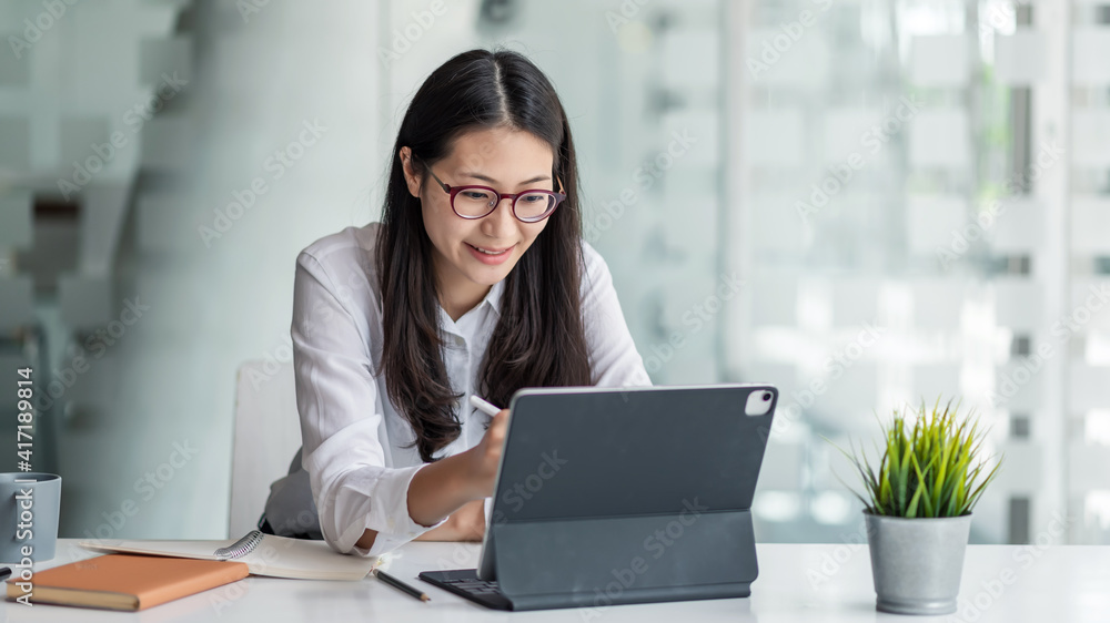 Young Asian businesswoman is happy to work at the modern office using a tablet. Young Asian businesswoman is happy to work at the modern office using a tablet.