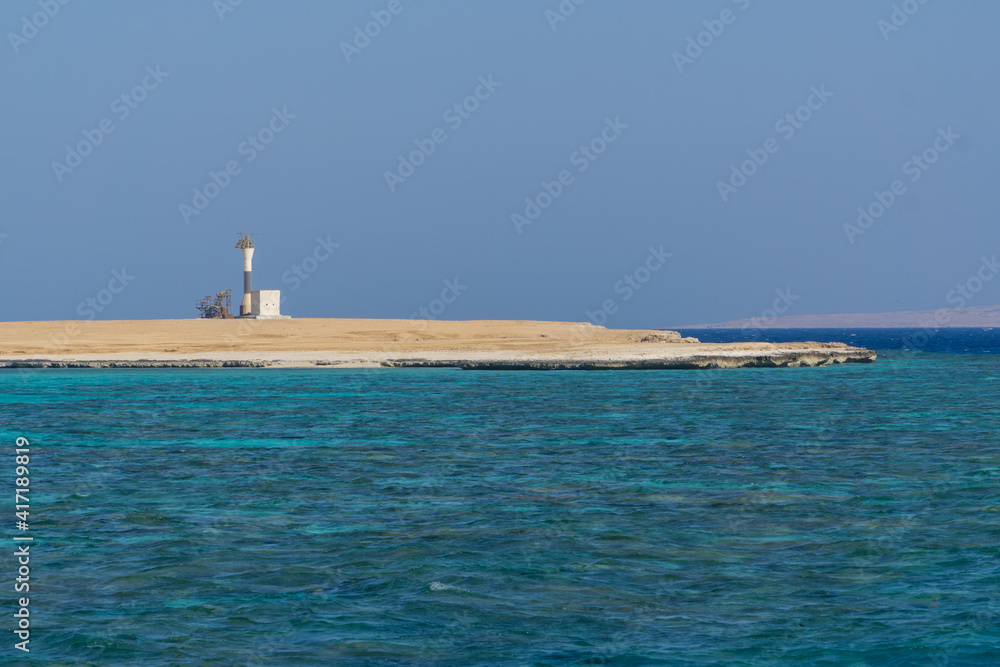 Lighthouse on sore with blue water and sand beach Lighthouse on sore with blue water and sand beach