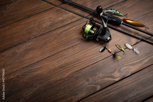Fishing tackle - fishing spinning rod, hooks and lures on wooden background. Active hobby recreation concept.