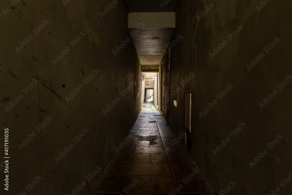 A dark, spooky corridor leading to a lit area