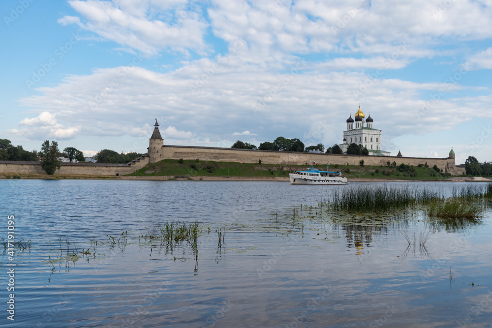 Pleasure boat on the river Velikaya opposite Trinity cathedral in Pskov Krom (Kremlin). Russia