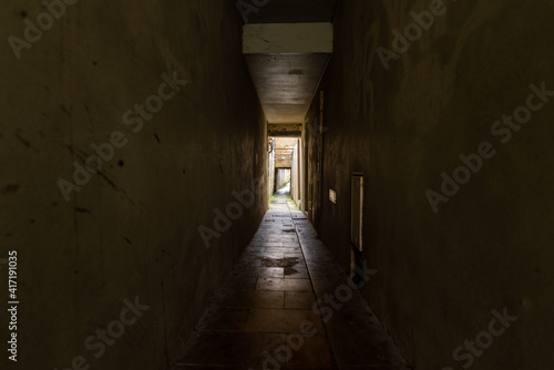 A dark, spooky corridor leading to a lit area