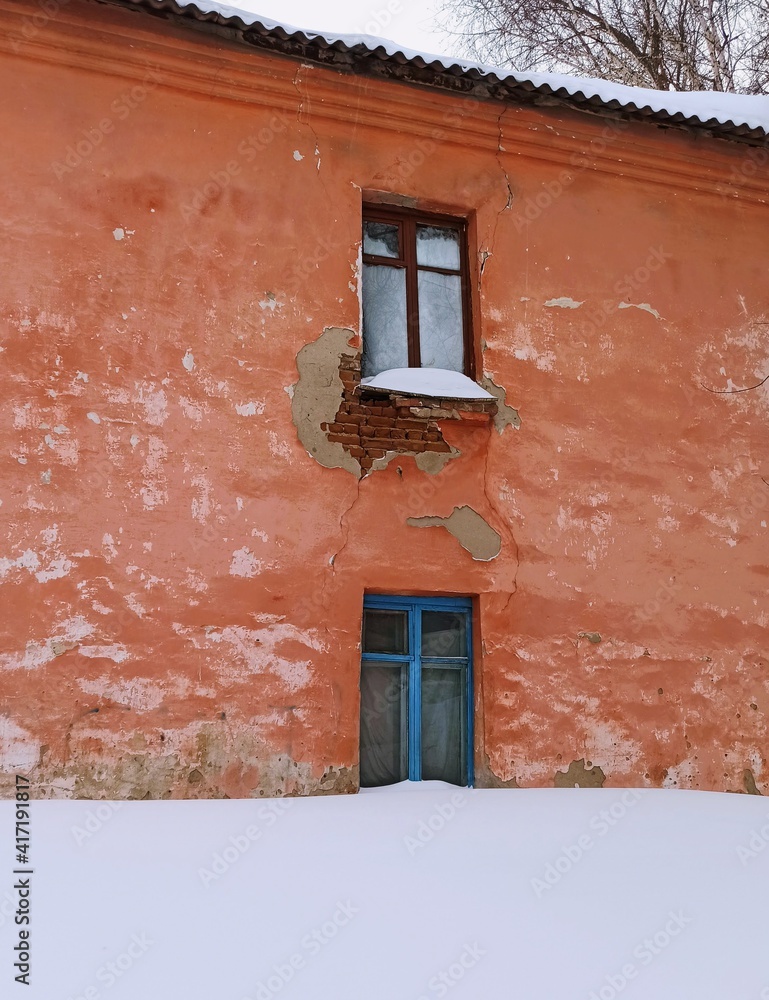 top window in a ruined orange house