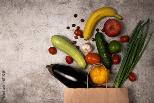 Healthy lifestyle and food concept. Vegetables and fruits falling out from paper pocket, cucumber, tomatoes, pepper, apple, bannans, nuts. photo