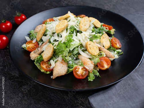 Caesar salad with chicken breast and parmesan cheese on bleak table