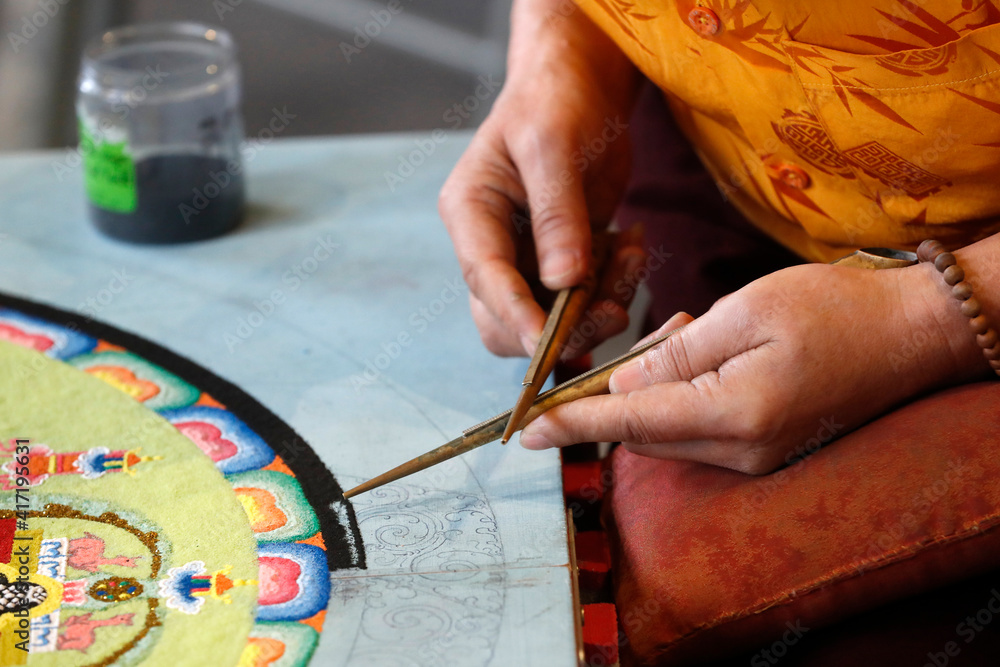 Obraz premium Tibetan monk working on sand mandala. Close-up. France. 25.02.2017