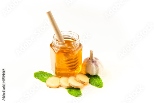 Glass jar of honey with ginger, mint and lemon isolated on a white background