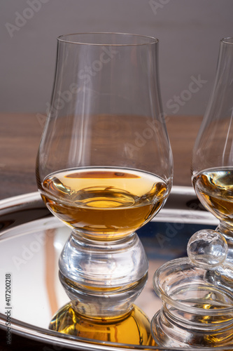 Tasting glasses of single malt scotch whisky served on steel mirror tray with reflection