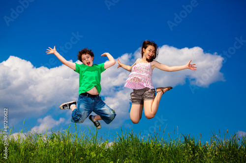 Girl and boy running  jumping against blue sky 