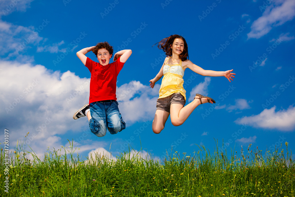 Girl and boy running, jumping against blue sky
Girl and boy running, jumping against blue sky