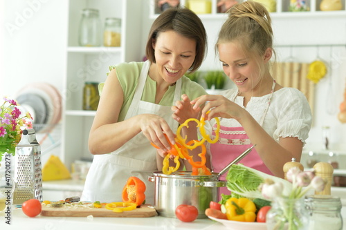  girl with her mother cooking together at kitchen