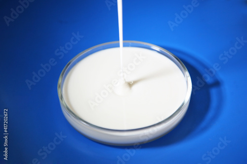 Liquid plastisol, rubber of blue, green, white, black, yellow or pulling paint is poured into a transparent round plate on a white background.