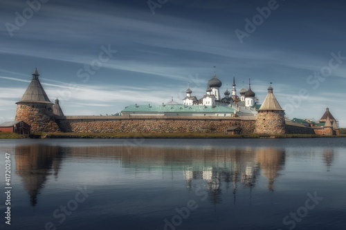Large stone and ancient monastery on a sunny day on the shore of the lake