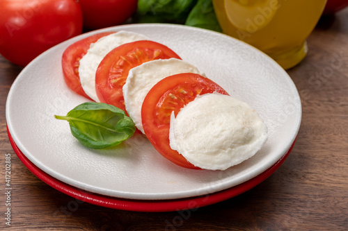 Tasty italian vegetarian food, fresh soft white mozzarella cheese served with red tomatoes and green basil