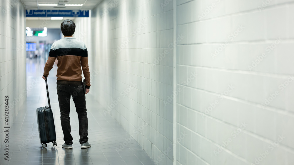 Fototapeta premium Travel insurance concept. Male tourist or passenger man carrying suitcase luggage and digital tablet walking in airport terminal.