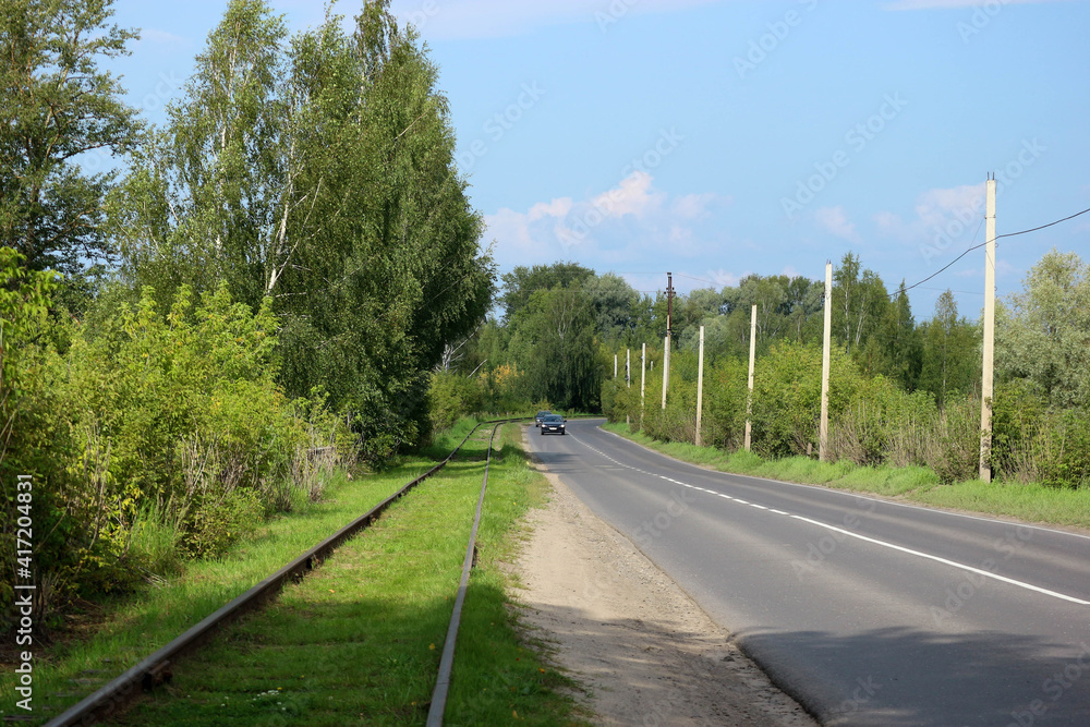 railroad tracks along the road in the countryside